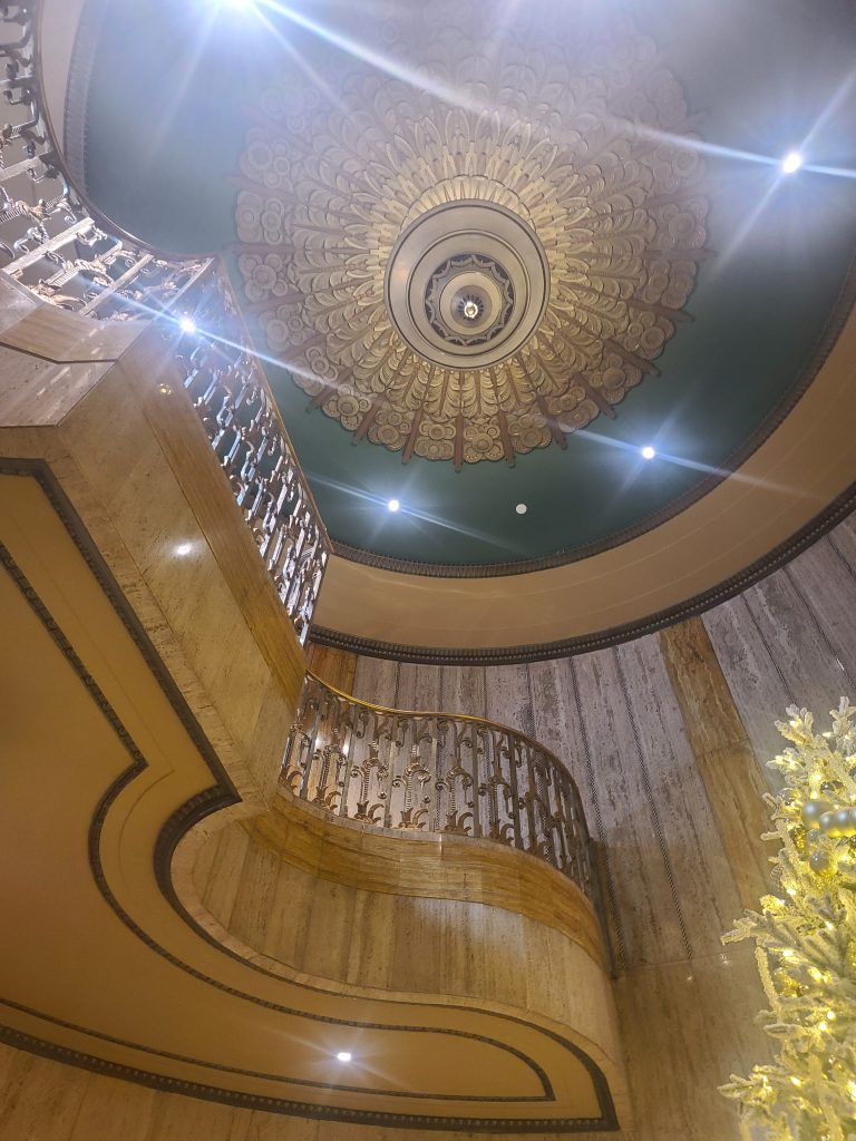 Restored decorative ceiling and hand-polished bronze staircase railing inside a historic building