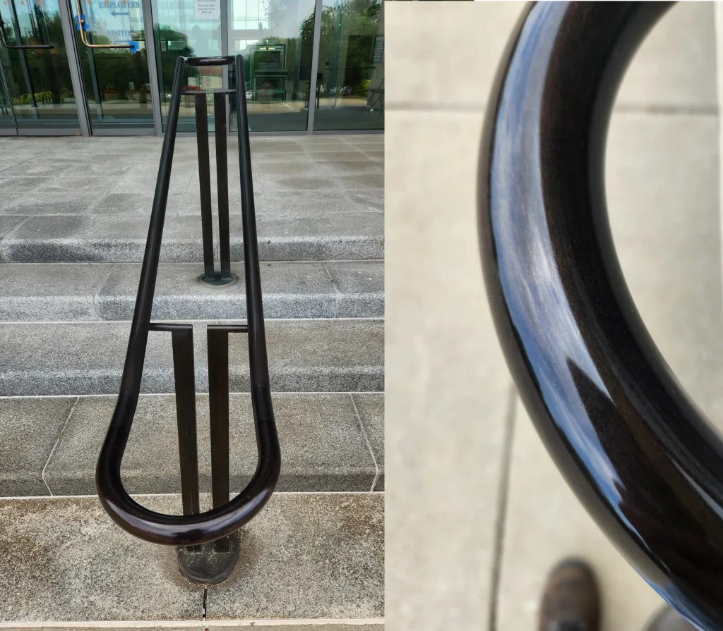 Refinished architectural handrail with glossy dark bronze finish on a commercial staircase